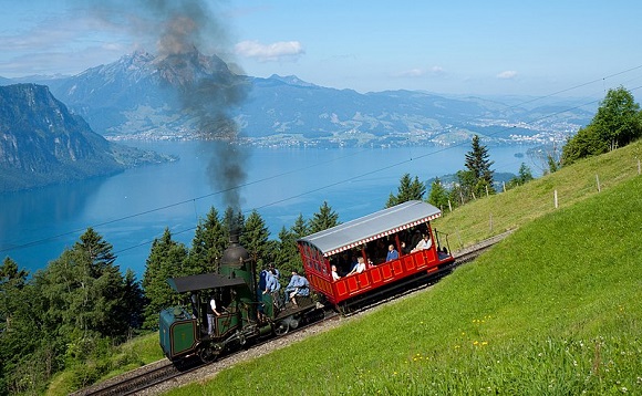Das Bild zeigt die Vitznau-Rigi-Bahn, wie sie einen Berg am Vierwaldstättersee hinabfährt.